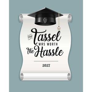 Blue gray graduation backdrop with a white diploma scroll, black graduation cap and tassel, 2027, and decorative lettering reading The Tassel Was Worth The Hassle.